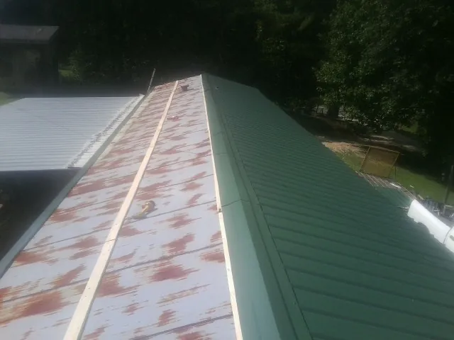 Old rusted panels beside newly installed green metal roofing — Wind Damage Roof Repair by Roofing Brothers in Morrow