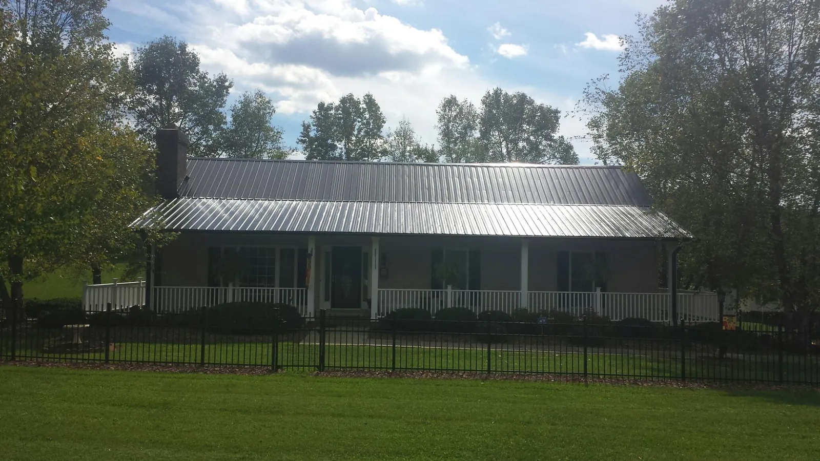 Gray metal roof on a brick ranch with a full width front porch — Gutter Guard Installation work by our crew in Morrow