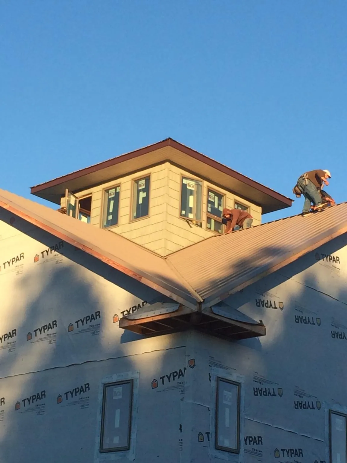 Roofers working around a rooftop cupola on a new metal roof at sunset — Roof Waterproofing in Morrow by Roofing Brothers